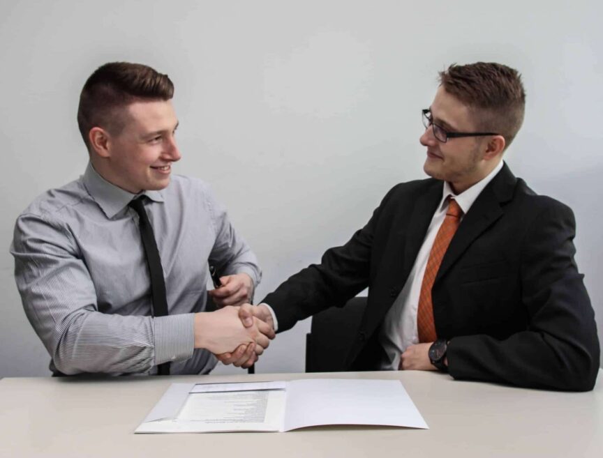 two men facing each other while shake hands and smiling